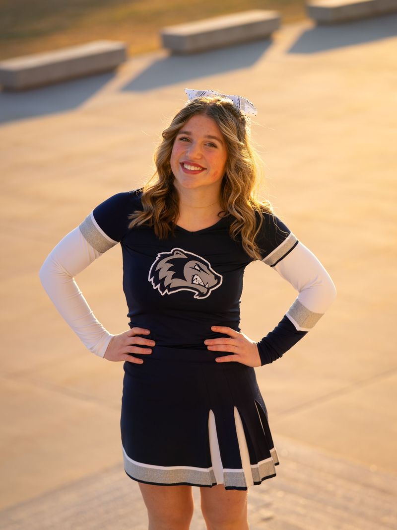 Cheerleader in a navy uniform with hands on hips, bright warm light
